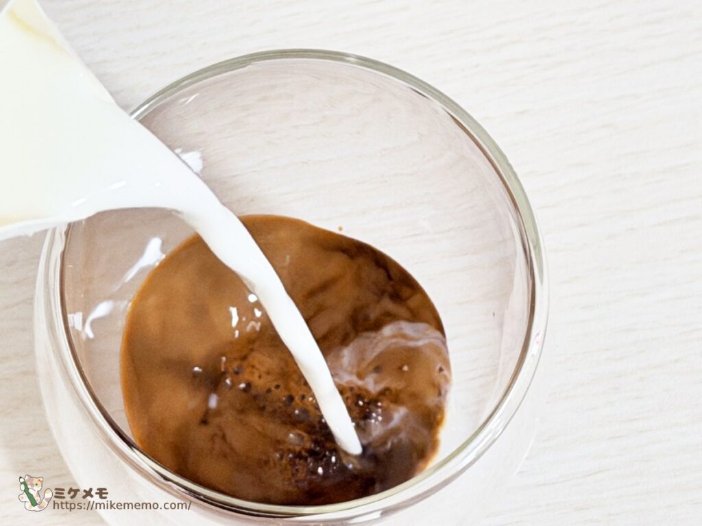 グラスのコーヒー液に牛乳を注いでカフェラテを作る様子