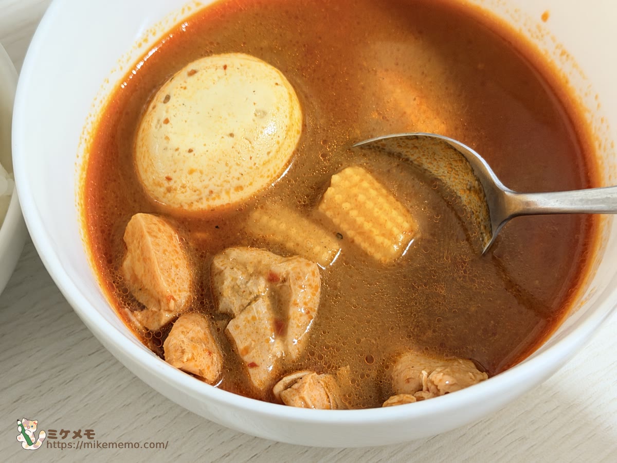 スープカレーの中のゆで卵とチキンとヤングコーン