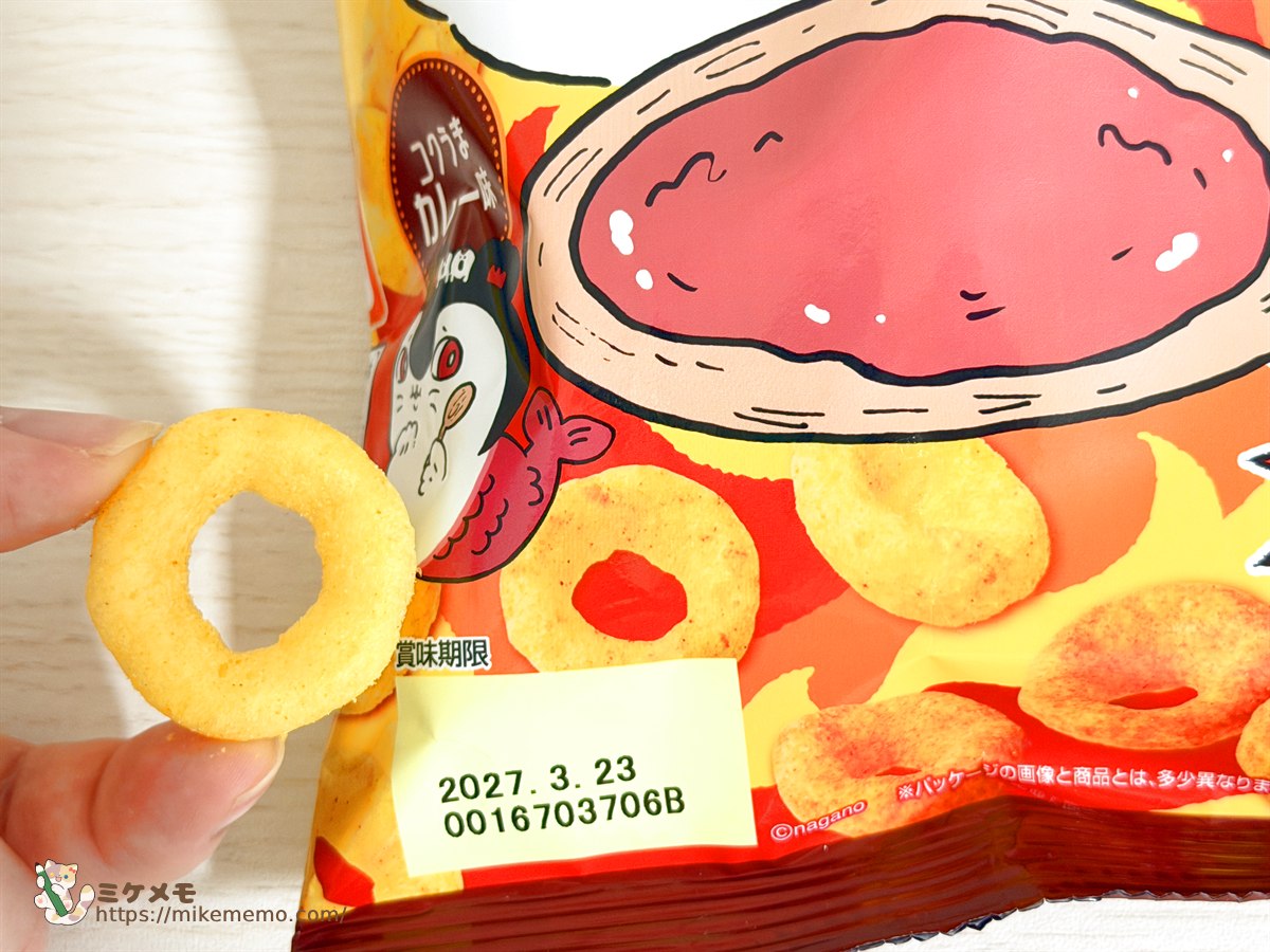 指でつまんだカレースナックとパッケージの写真の比較