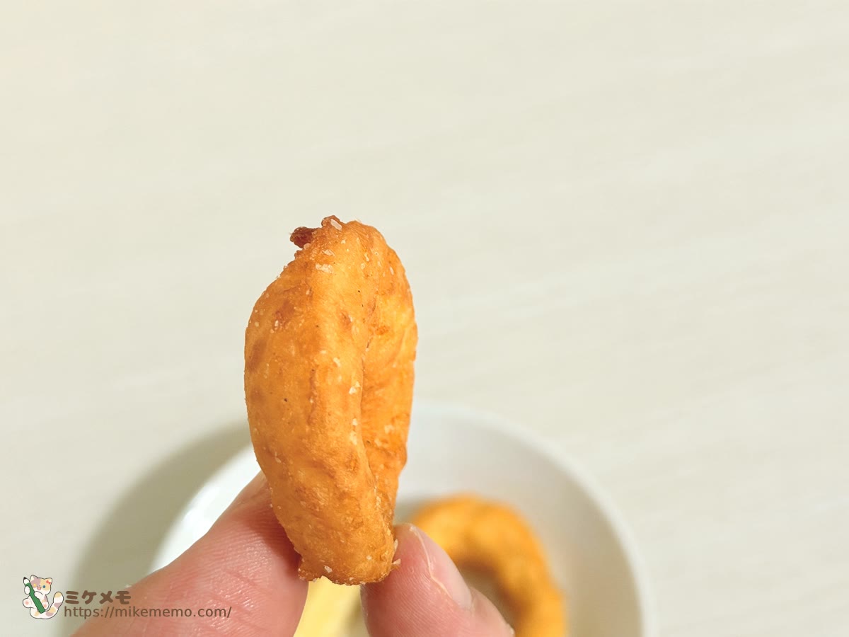 指でつまんだオニポテスナックのオニオンフライ