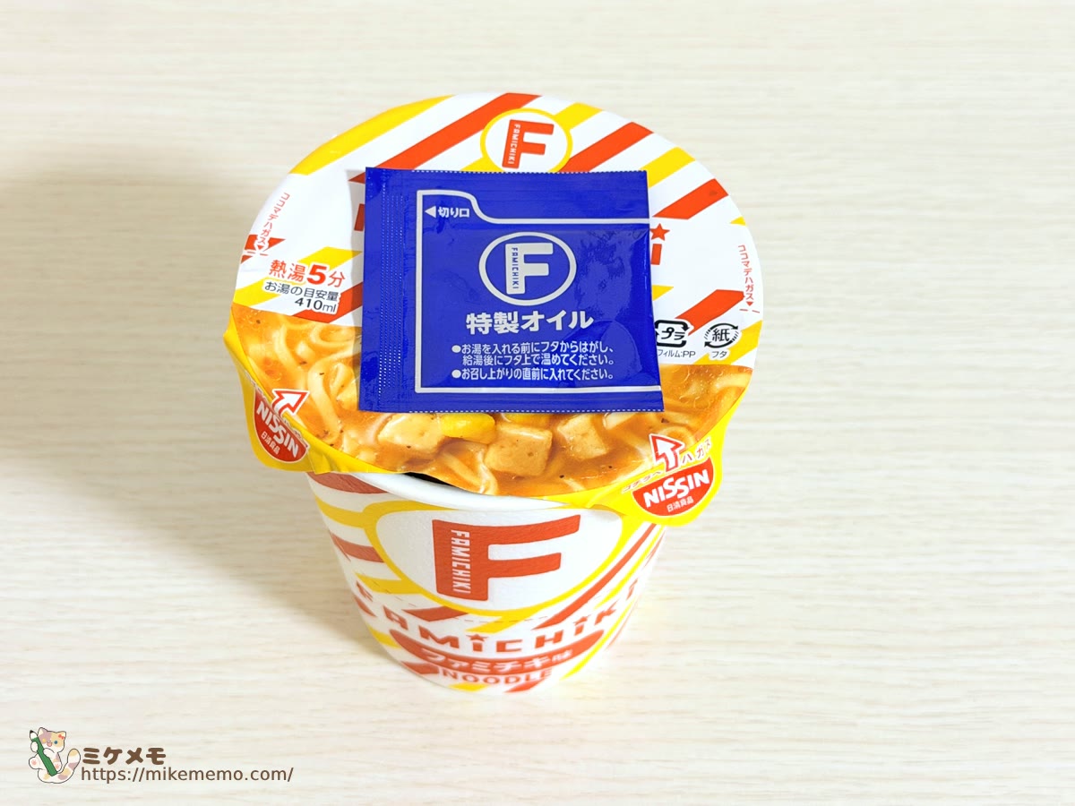 正面から見たファミチキ味ヌードルのフタと特製オイル